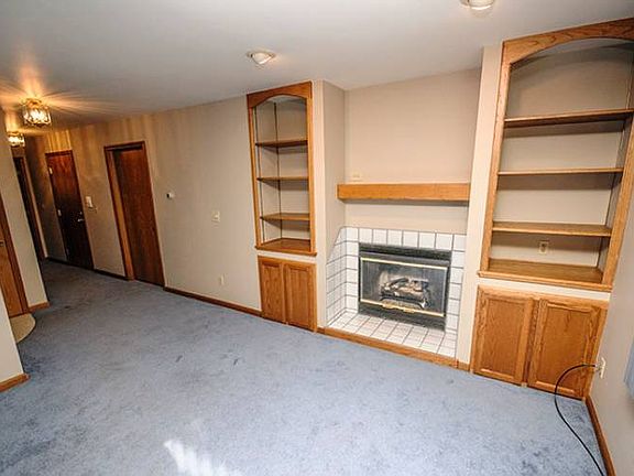 View of the front entry door from the living room (13x26) highlights the gas fire place and built in shelves which make this unit unique from some of the other fifteen units in the community.