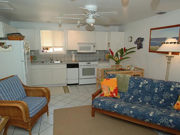 Cottage kitchen and living area. Kitchen has dishwasher, full refrigerator, electric stove, large sink, AC and ceiling fan.