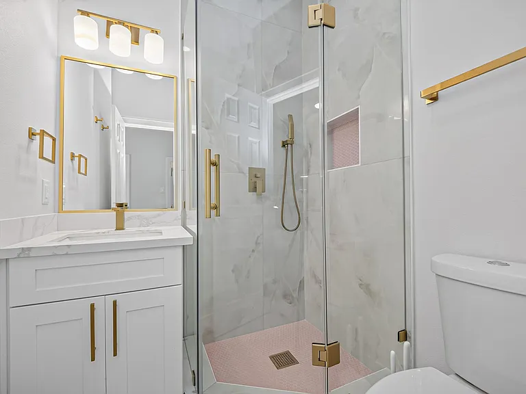 Updated bathroom with a sleek vanity, framed mirror, and glass-enclosed shower with tile surround and modern fixtures.