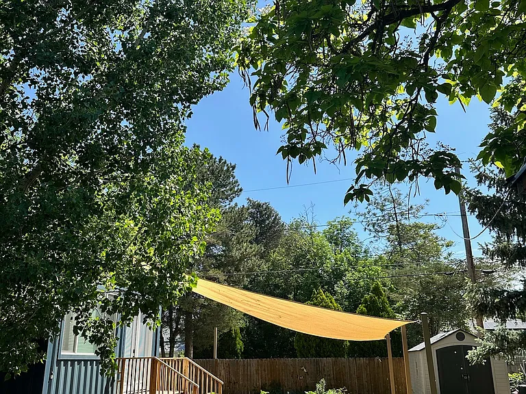 Spacious flagstone patio with sun sail shade, raised planter boxes, backyard office, and a versatile garden/bike shed.