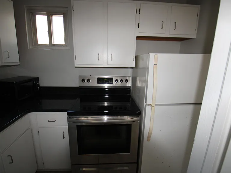 Kitchen with electric range, refrigerator & microwave.