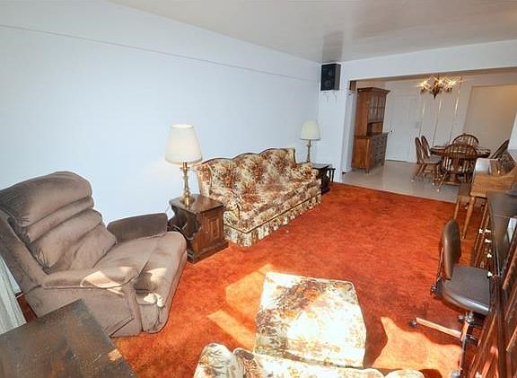 Large Sunny living room has covered hardwood floors and opens to the dining foyer.