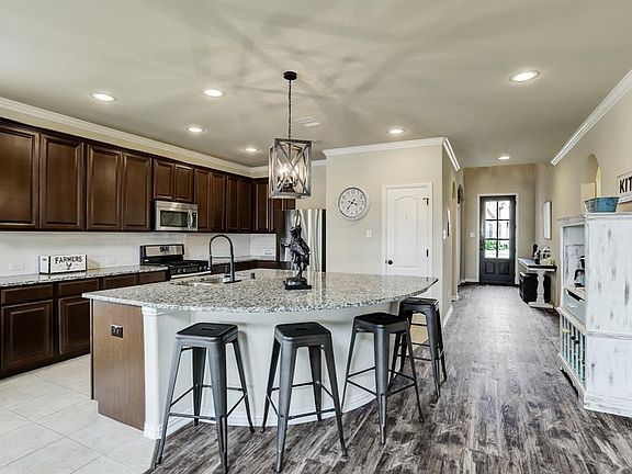 The kitchen boasts stainless steel appliances, a gas range, a large walk in pantry, upgraded lighting, and an oversized island.