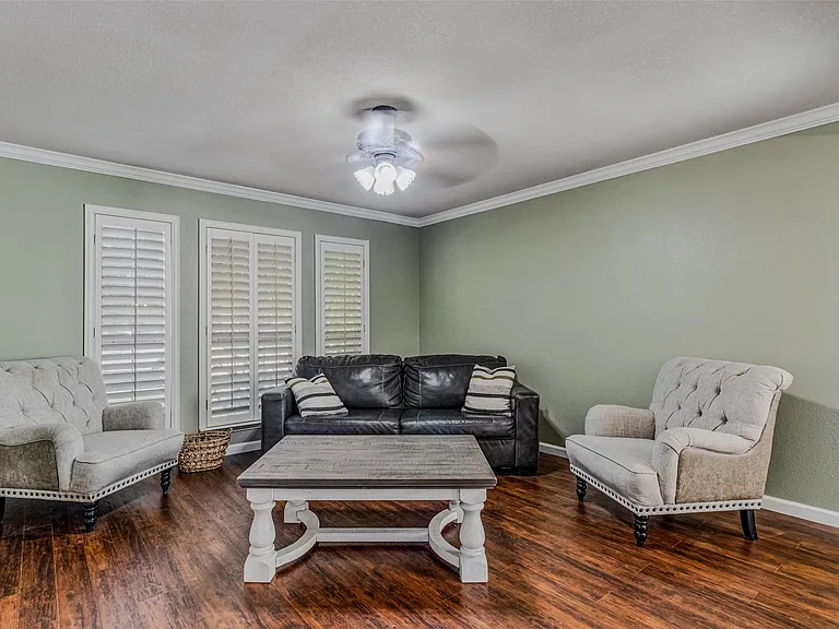 Spacious room featuring rich wood-finish flooring, light green walls, and white crown molding