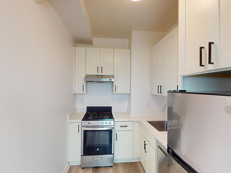 Kitchen with cabinetry, stainless steel stove, range hood, and refrigerator