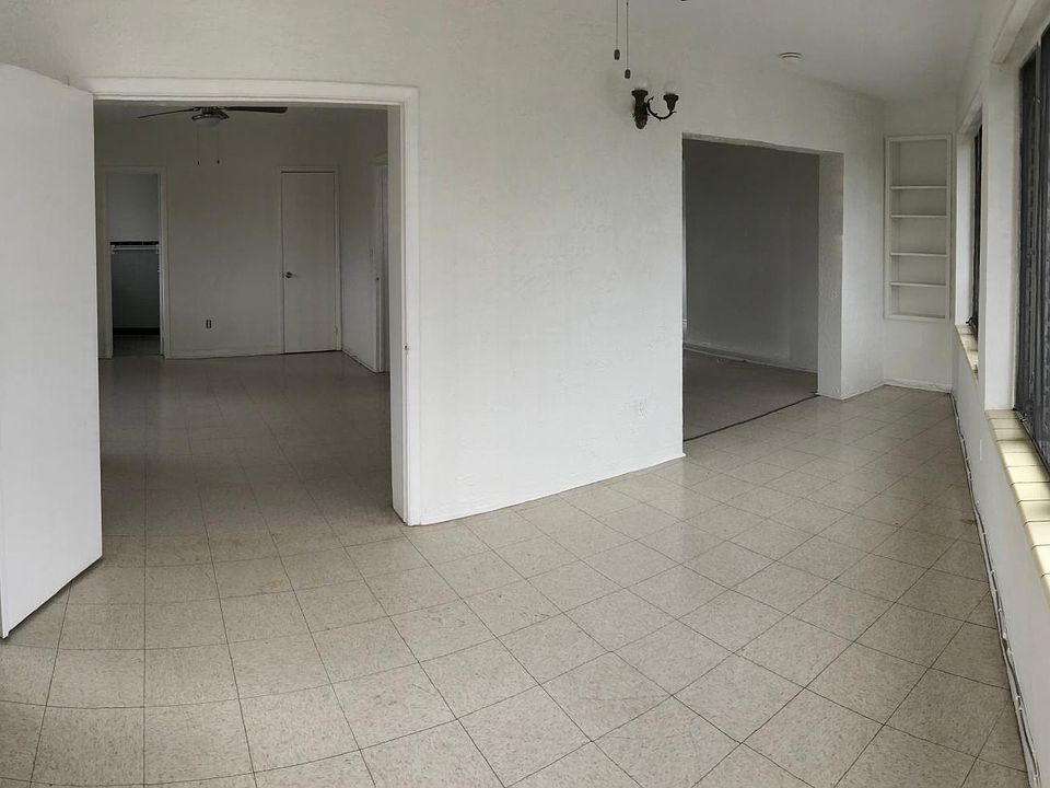 Main entrance showing guest room (double doors at left) and living space that doubles as dining area. New ceiling fans throughout.
