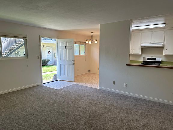 Living room showing front doorway, dining room, and kitchen.