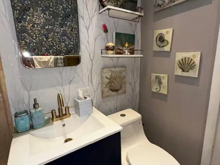 Stylish half bath with a single-sink vanity, decorative mirror, and convenient shelving for everyday essentials.