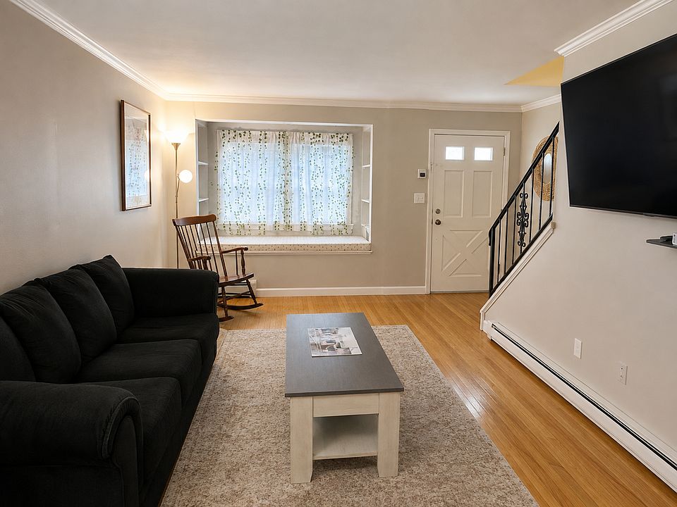 Living room with hardwood floors, crown molding, and open stairs to the bedroom level