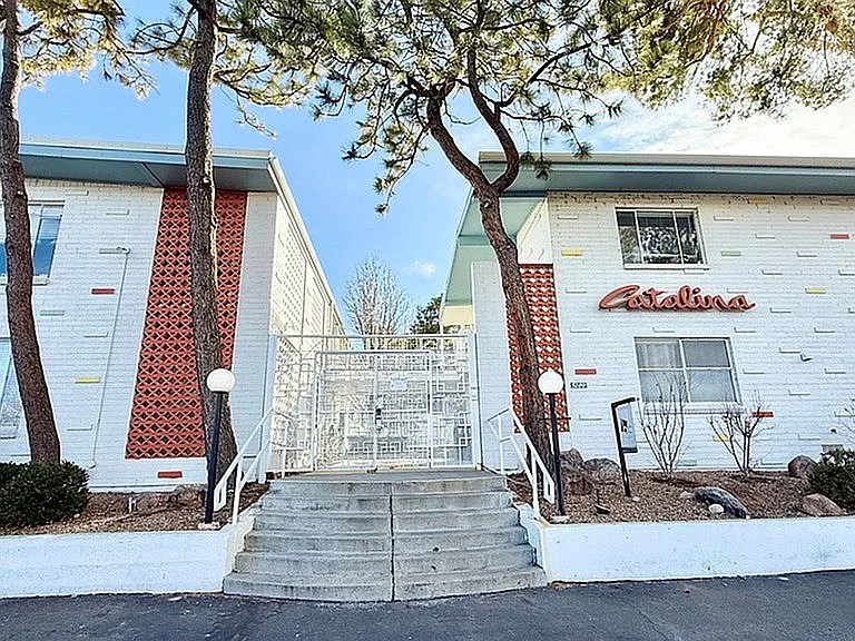 Charming mid-century modern apartment building with unique brick and colorful accents, surrounded by serene landscaping and mature trees.