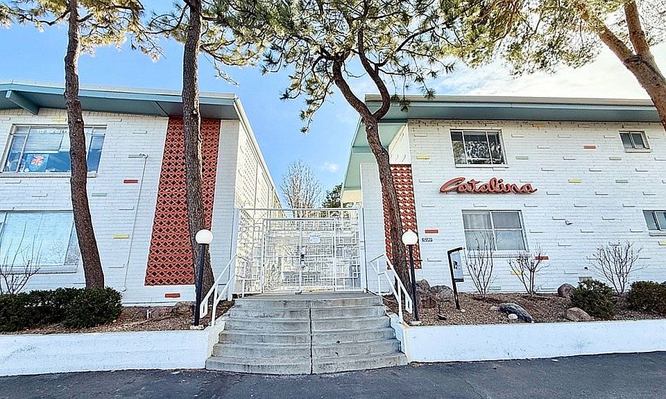 Charming mid-century modern apartment building with unique brick and colorful accents, surrounded by serene landscaping and mature trees.