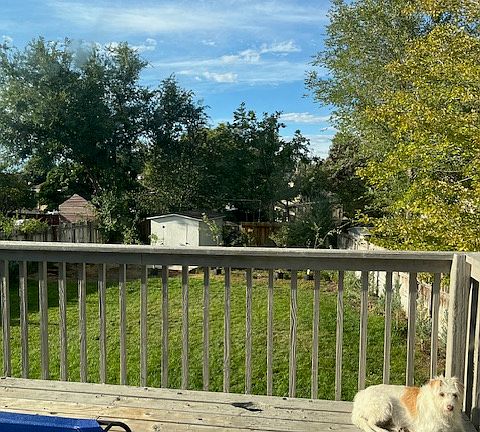 Large fenced yard with storage sheds, deck