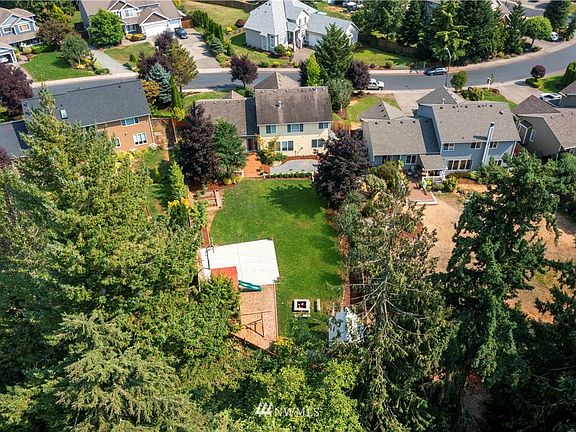 This fully fenced yard offers expansive entertaining deck, garden space, basketball court, play set, outbuilding and awning~Surrounded by trees and greenbelt, enjoy privacy in your own backyard retreat