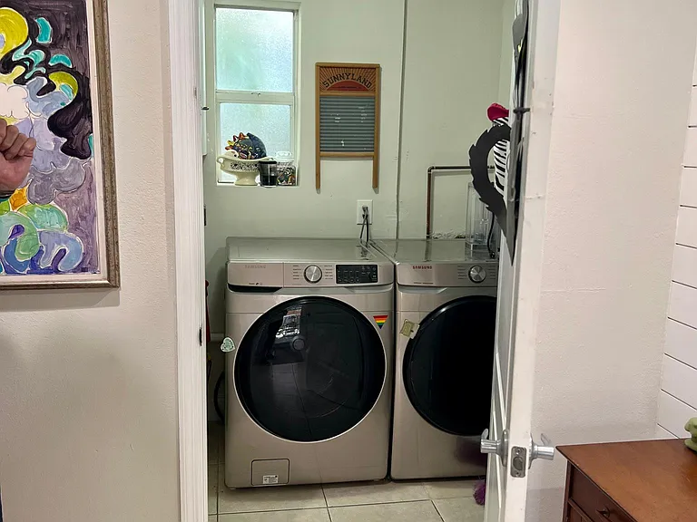 Large walk-in laundry room with upper cabinets for storage and a laundry sink.