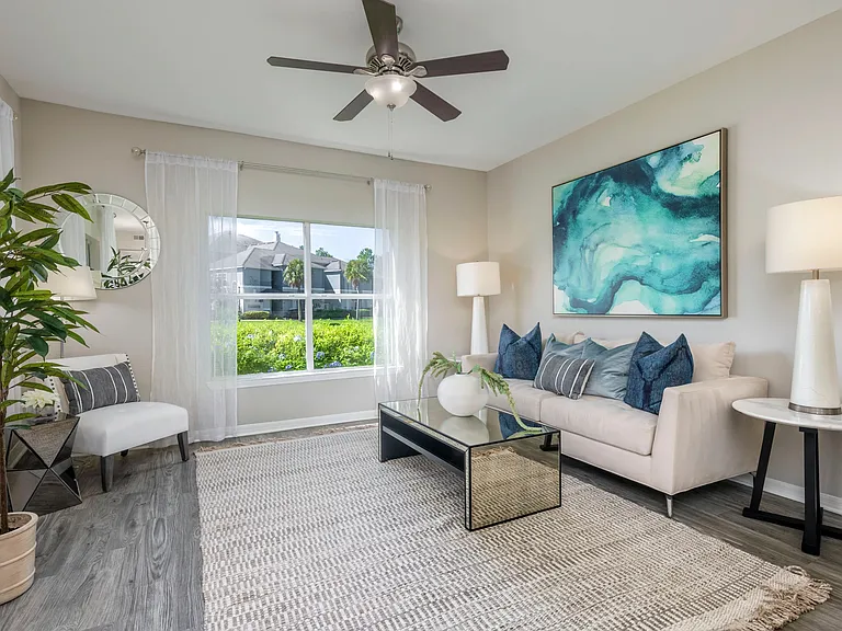 Bask in the natural light of your spacious living room, with large windows that frame the outdoors and a ceiling fan that gently circulates the air. Your private sanctuary awaits.