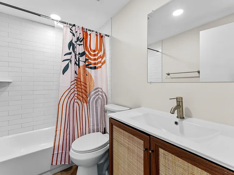 Full bathroom with a tub/shower combo, subway-tile surround, and a spacious vanity with integrated sink and mirror.