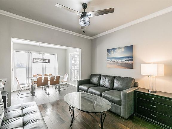 Living area featuring baseboards, wood finished floors, a ceiling fan, and crown molding