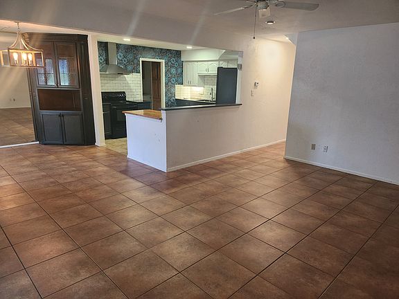 Open living, dining, and kitchen areas with built in cabinet and dining bar