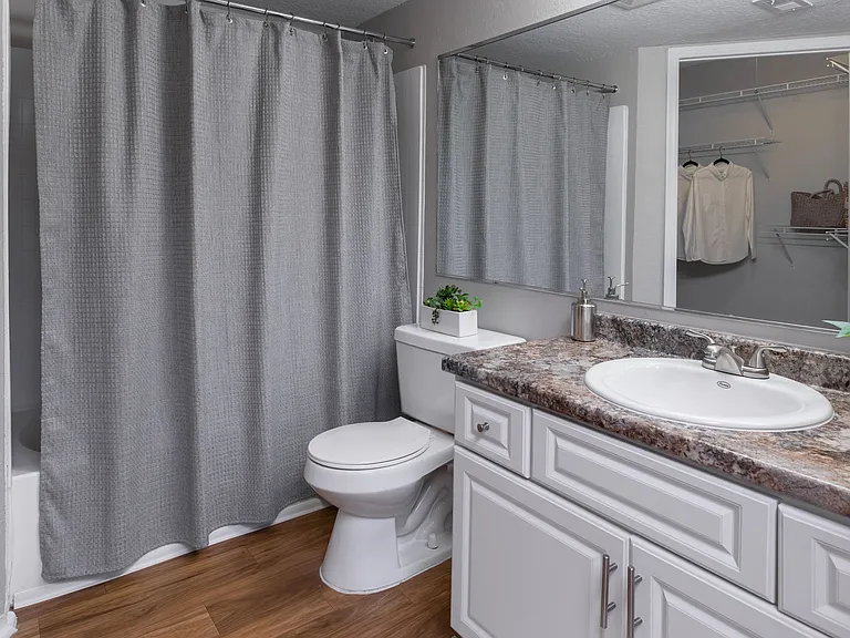 Enjoy a bright and inviting bathroom with sleek countertops, a large mirror, and stylish cabinetry.