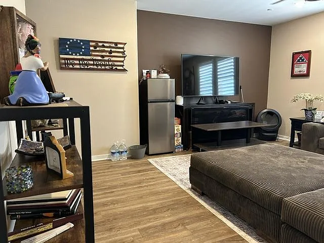 Shared lounge area with seating, a media setup, and a mini fridgeideal for relaxing, streaming, and quick snacks.