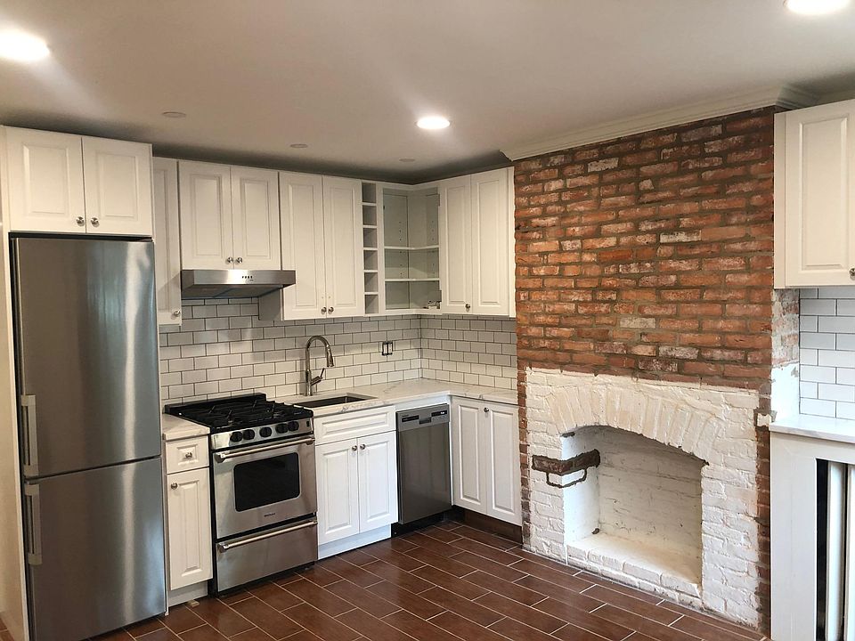 Spacious renovated kitchen with high ceilings and stainless steel appliances, including dishwasher