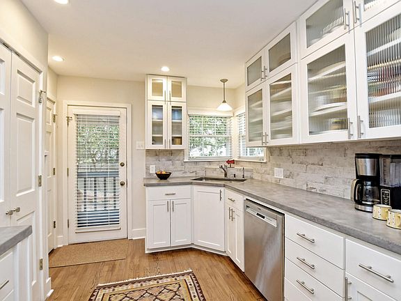 Recent kitchen with white cabinets, concrete counter tops, SS appliances including a gas range.