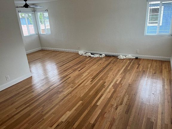 Living room entrance to the home. Freshly refinished hardwood floors. Ceiling fan and shutter window coverings