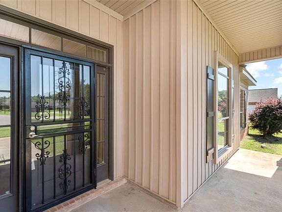 Front entrance featuring a black wrought iron security door with decorative scrollwork, surrounded by sidelight windows and a transom window