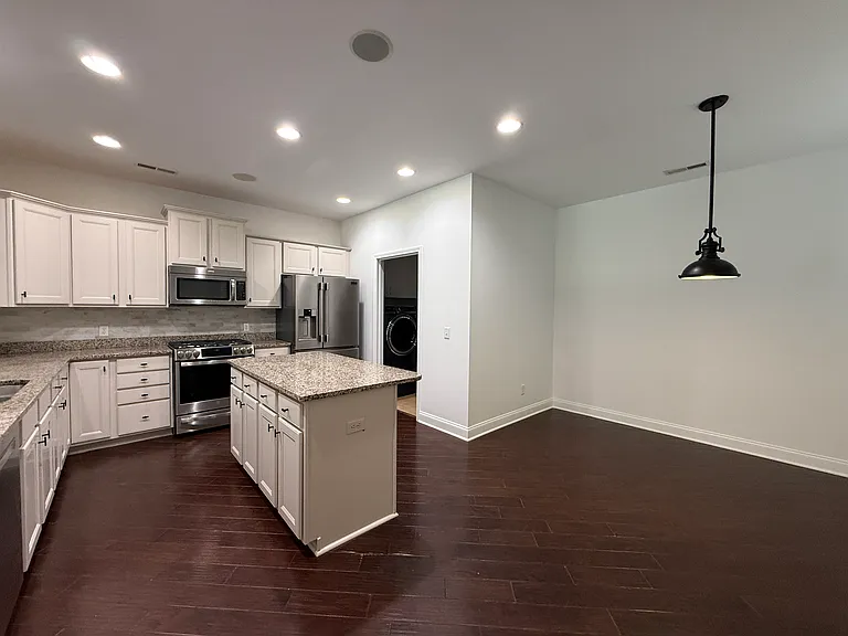 Gourmet kitchen featuring premium stainless steel appliances, a modern gas range, granite countertops, and a functional central island with a matching breakfast nook."