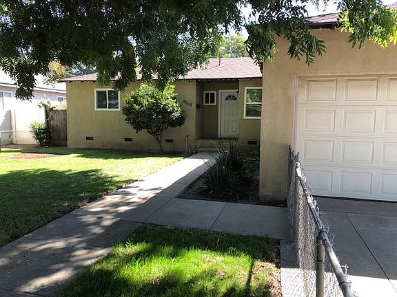 View of the front yard, front door, garage door from the sidewalk.