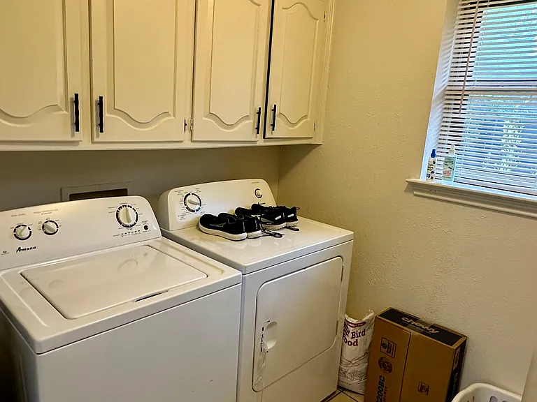 Laundry area featuring full size washer and dryer area, cabinet space, light tile patterned floors