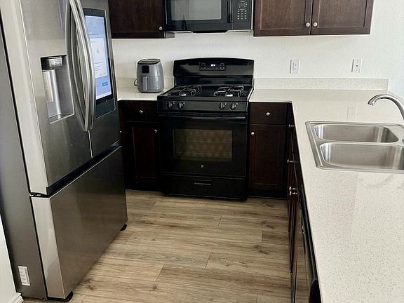 Efficient kitchen with dark cabinetry, ample counter space, and stainless steel fridge plus gas range and built-in microwave.