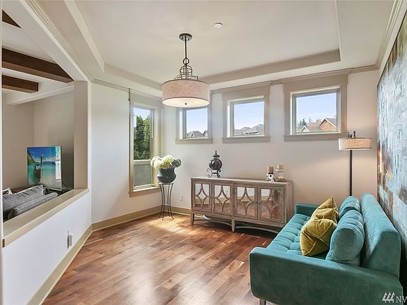 Sun-drenched dining room with chic chandelier and walnut hardwood floors.
