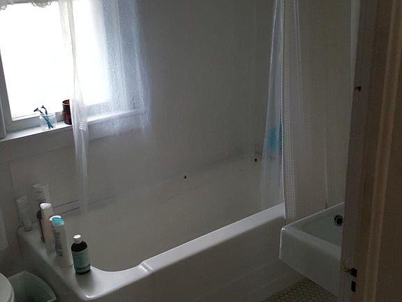 Bath with tiled floor, large window and exposed brick accent