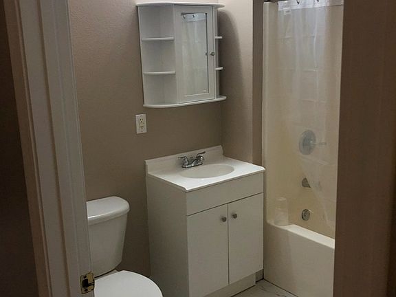 Bathroom with tub/shower combo, toilet and vanity.