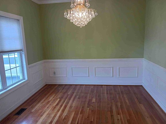 Formal dining room with wainscotting and chandelier.