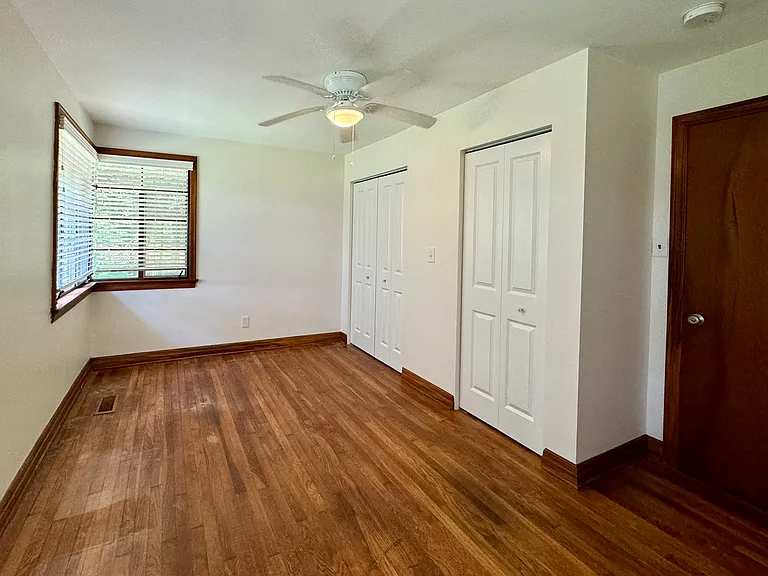Bedroom 1 with hardwood flooring.