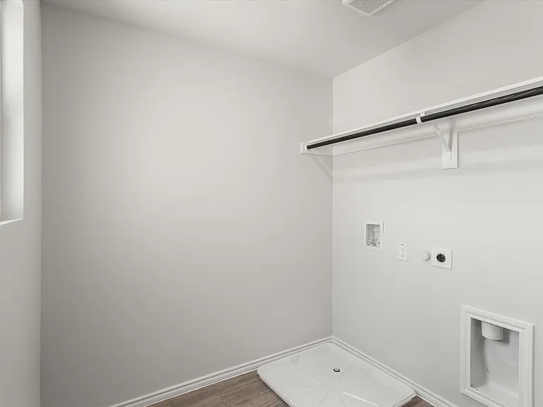 Dedicated laundry area featuring a window, wood-finish flooring, a wall-mounted clothing rod, and essential utility hookups