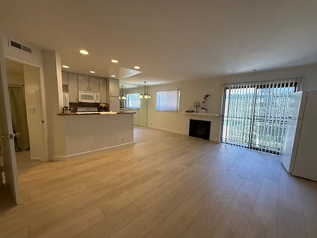 Living room/Dining area with faux fireplace & Kitchen with granite counter tops, stove, dishwasher, refrigerator & microwave