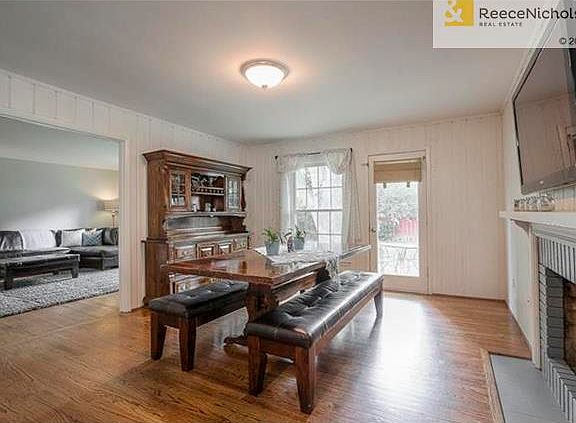 Dining/hearth room has gleaming hardwood floors with fireplace and opens to living room and kitchen.
