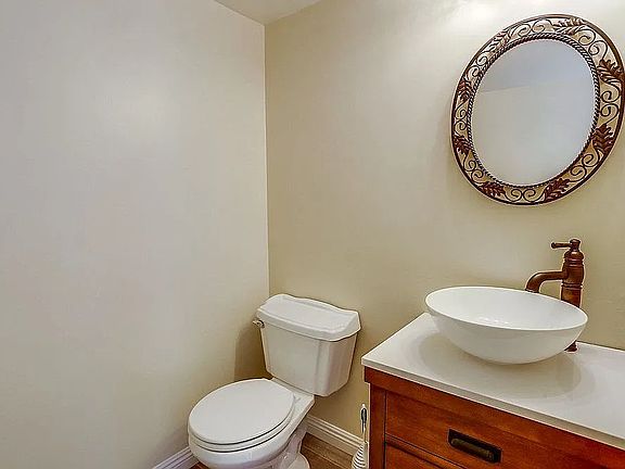 Stylish downstairs guest powder room featuring a modern vessel sink, warm wood vanity, and decorative mirror _ perfect for visitors and entertaining.