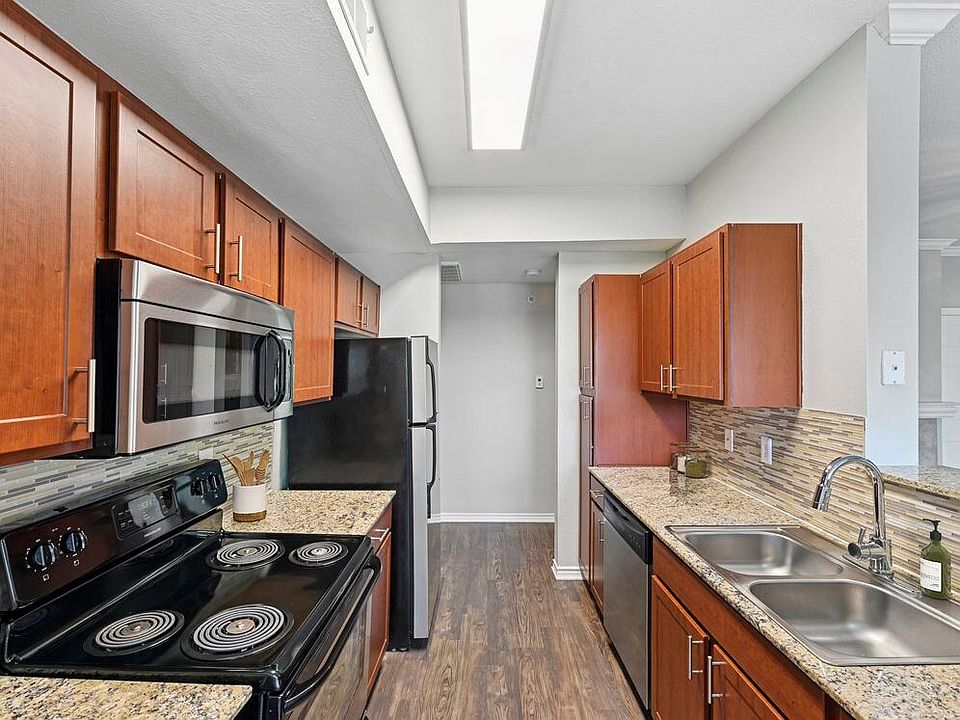 Kitchen with chestnut cabinetry, speckled granite countertops, tile backsplash, stainless steel appliances, and hard surface flooring