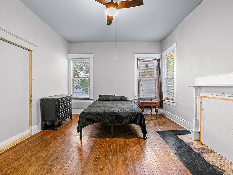 Spacious bedroom with hardwood floors, ceiling fan, and multiple windows for great natural light and flexible furniture layou
