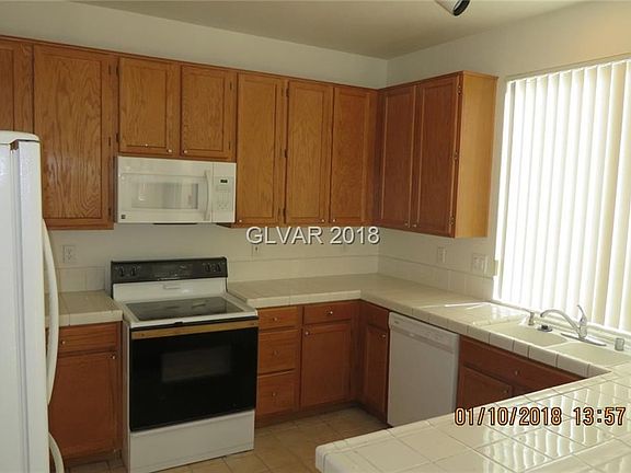 Kitchen with lots of tile counters and a breakfast bar.