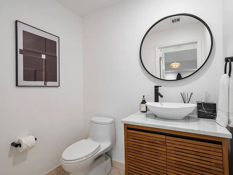 Simplicity meets sophistication. Featuring a natural wood vanity and chic circular mirror.