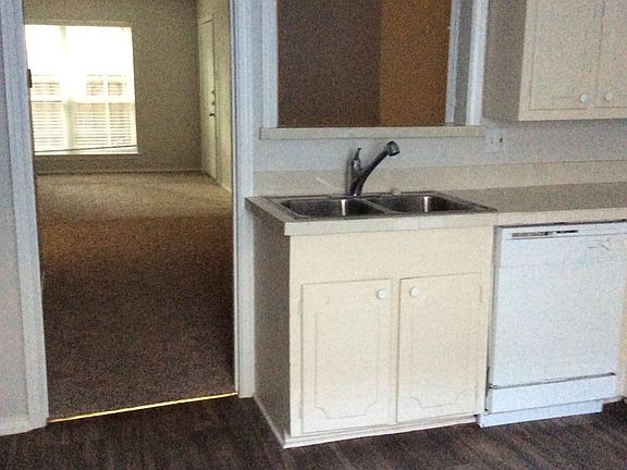 View from kitchen into dining and living room. Front door opens into the living room. The kitchen has a back door.