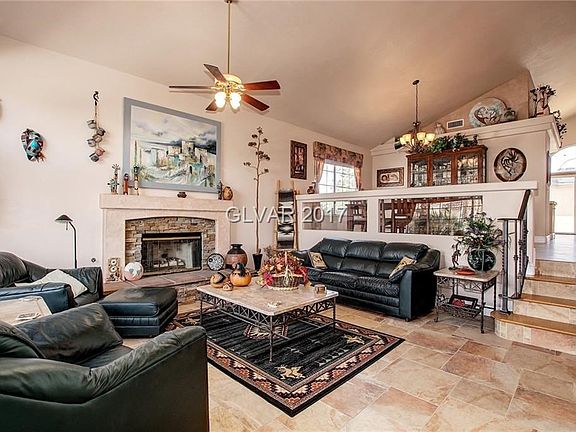 Living room with vaulted ceiling & tile floors...Fireplace has stacked stone surround..