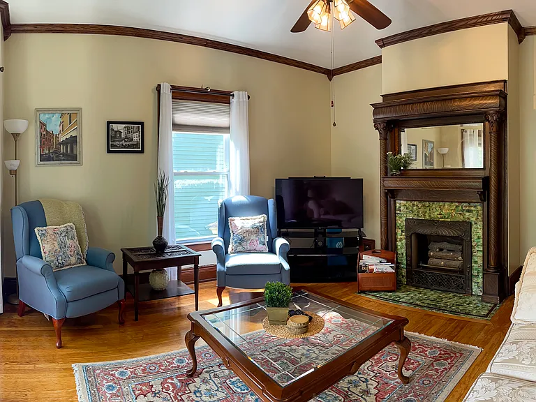 [Living Room] Spacious room with large windows, provides a beautiful view of a tree-lined street.