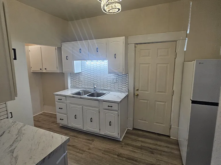 Kitchen in the back of the house with the back door leading to the backyard.
