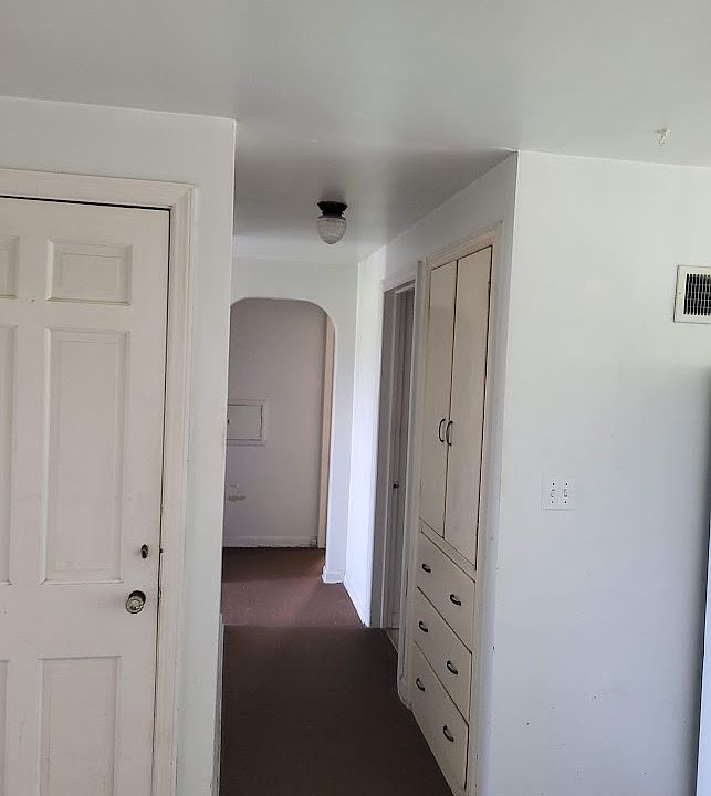 Hallway from Dining area to bathroom to 2 bedrooms. Built in Cabinetry and drawers for storage. Door on the left is to the upstairs storage area. The upstairs is not finished but does have storage shelving.